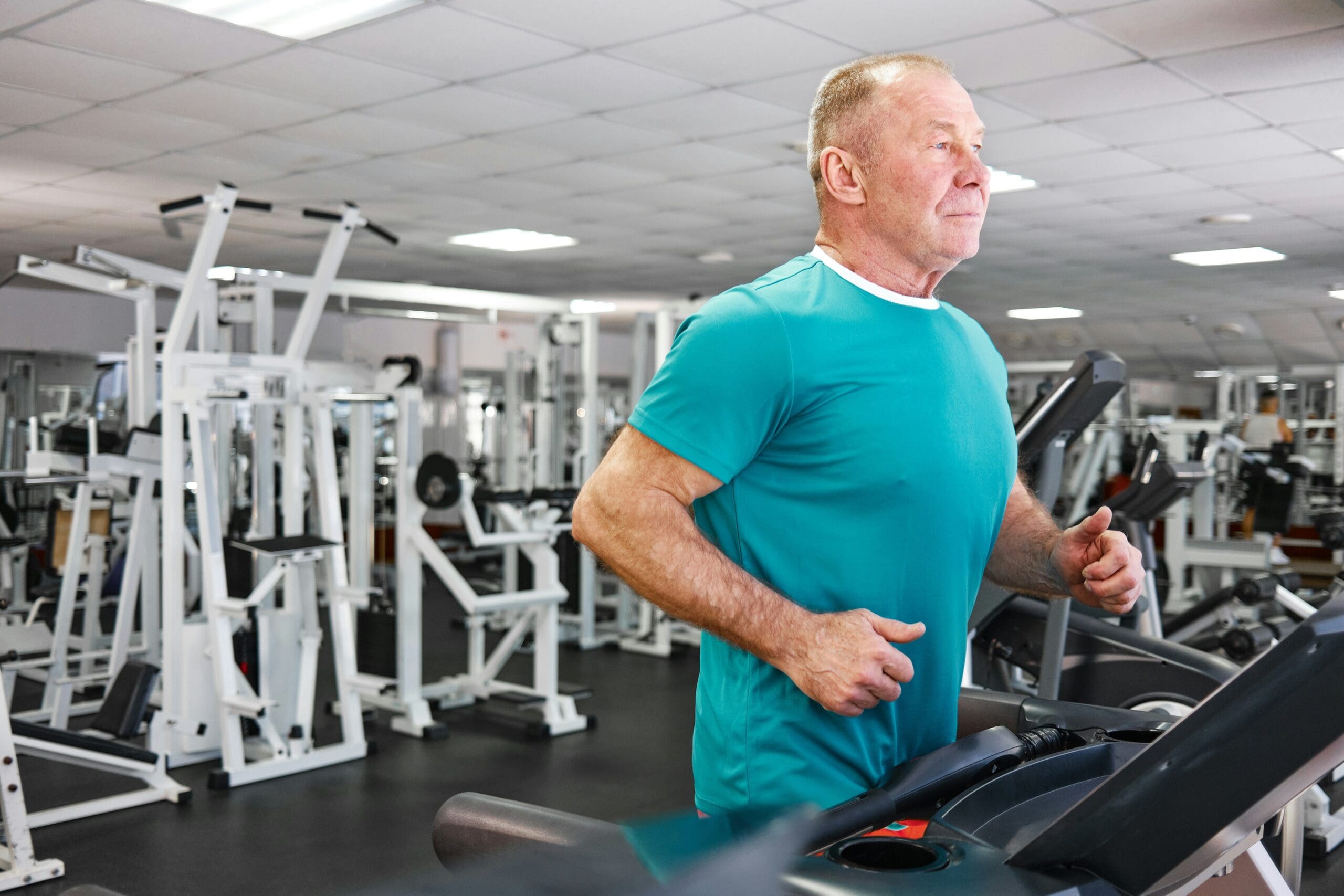 Older man jogging on a treadmill in a gym, representing sustainable weight loss through consistent exercise habits