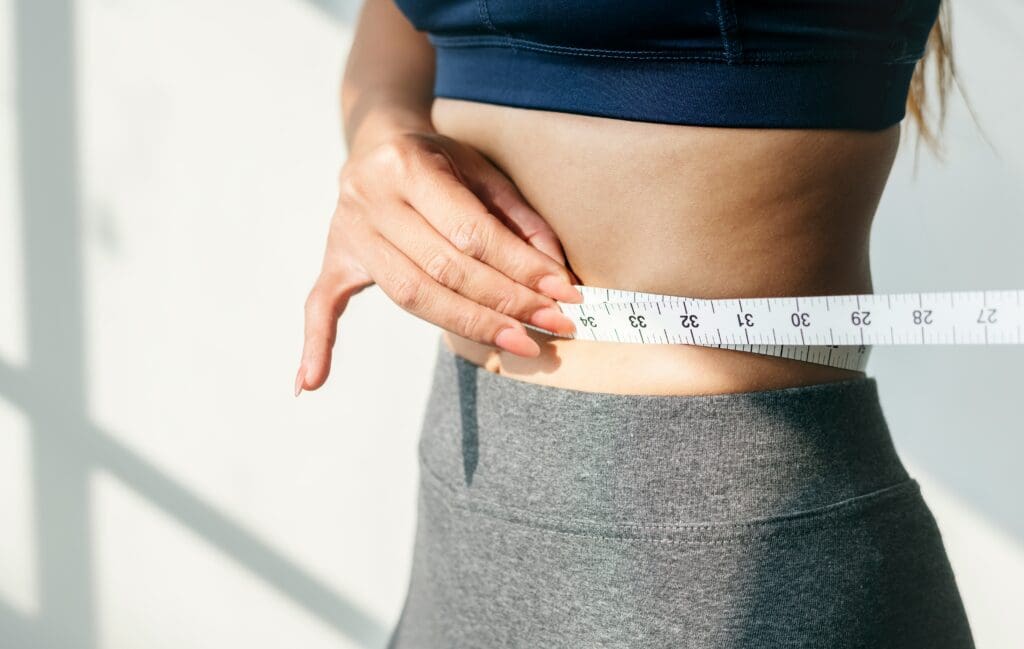 Woman measuring waist with tape for sustainable weight loss progress