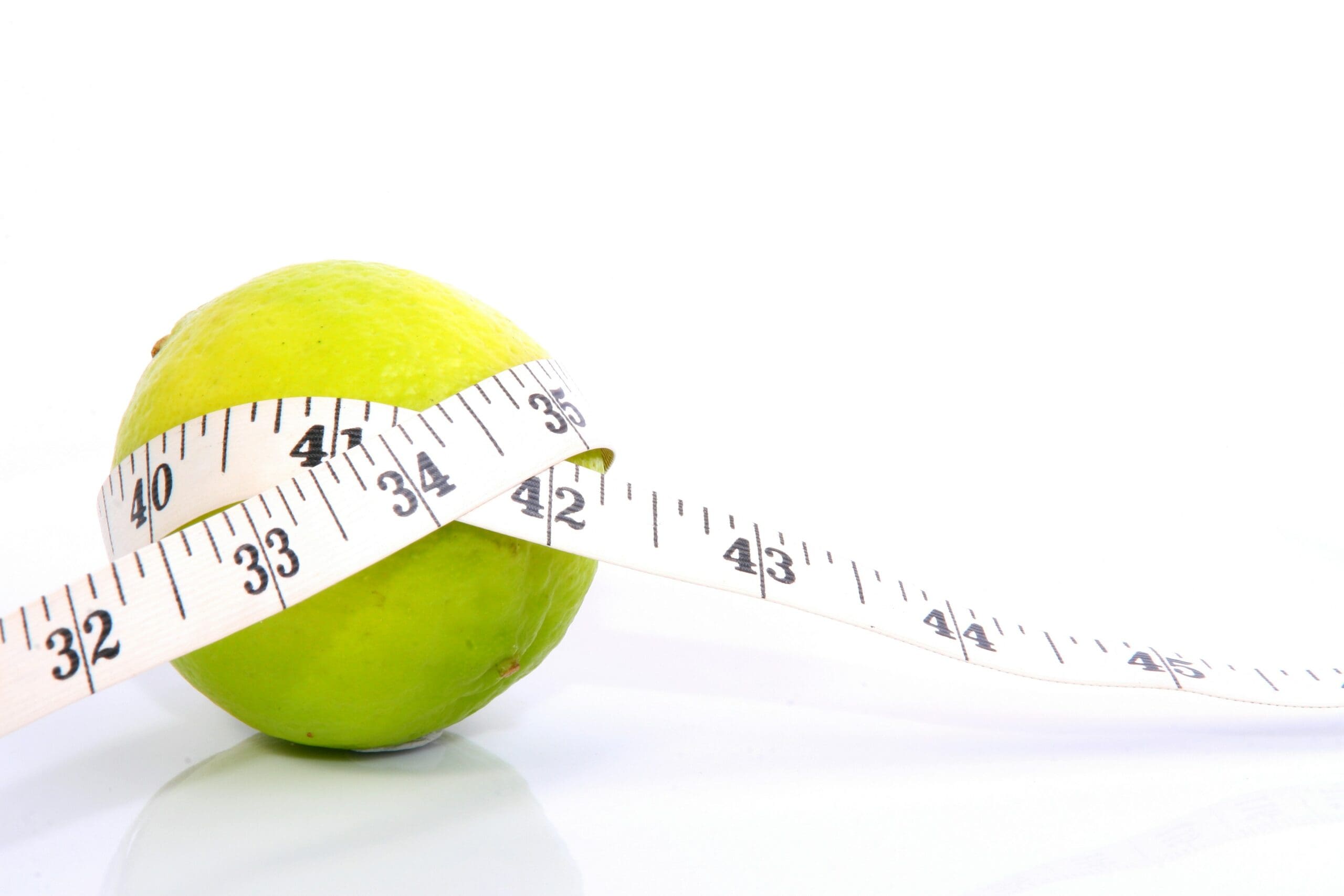 Green apple wrapped with measuring tape symbolizing weight loss maintenance and healthy habits